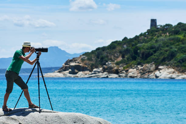 istock Photographer with tripod shooting sea landscape 639970220