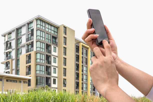 istock hand holding a smart phone and new condominium. 639972298