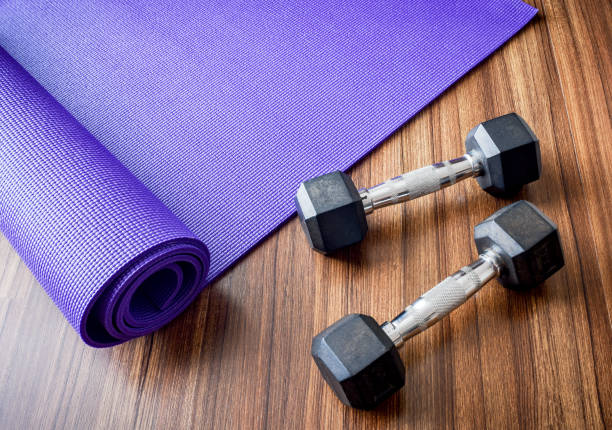 istock Two dumbbells on purple color Yoga mat background. 639975792