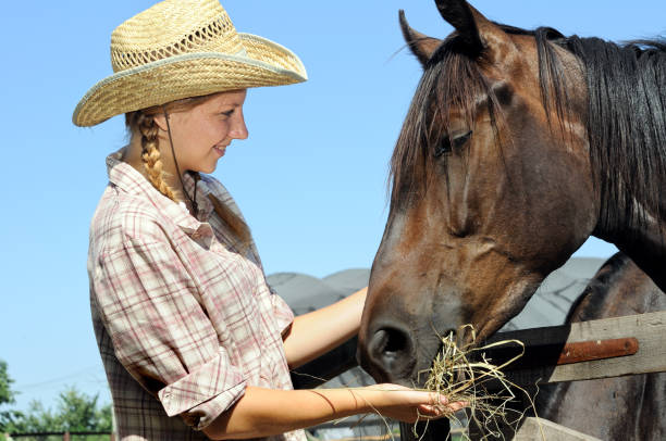 istock young cowgirl feeding horse 639978286