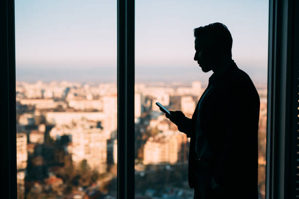 Sillouette of a businessman texting in his office.