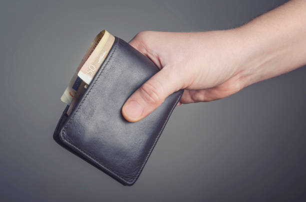 istock Leather wallet  in hand isolated on dark background 639985338