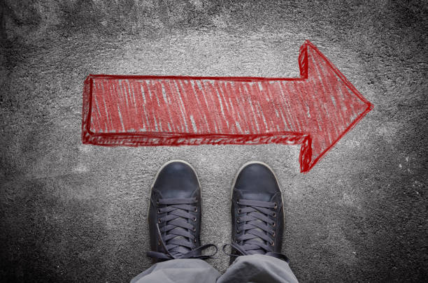 istock Sneakers on asphalt road with red arrow 640003534