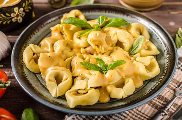 Tortellini with cheese sauce, basil and herbs