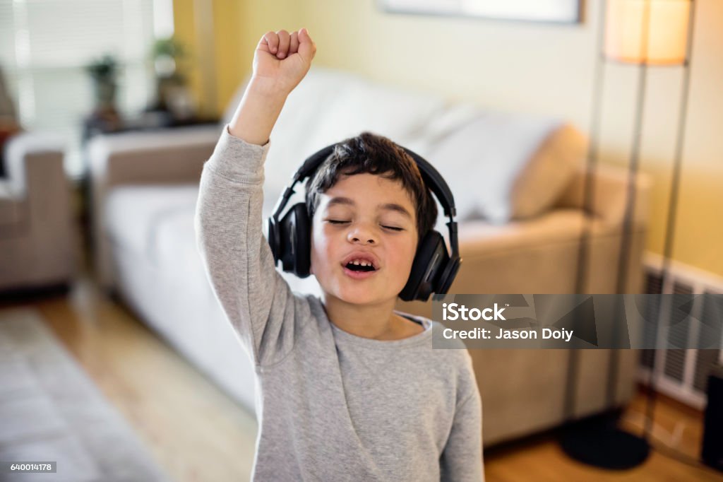 Child Rocking Out to Music Stock photo of a child listening to music on wireless headphones Child Stock Photo