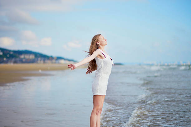 Beautiful young woman enjoying her vacation by ocean or sea, walking in water. People on sea vacation concept