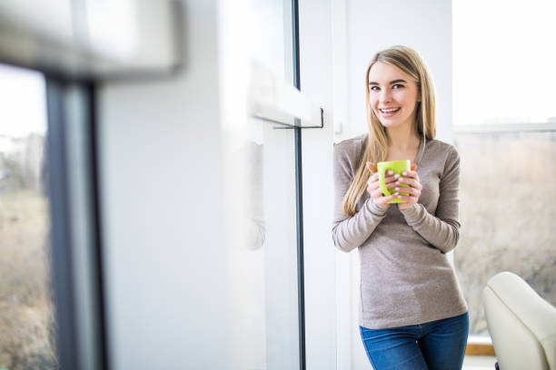 istock woman drink coffee against panoramic windows in office 640020486