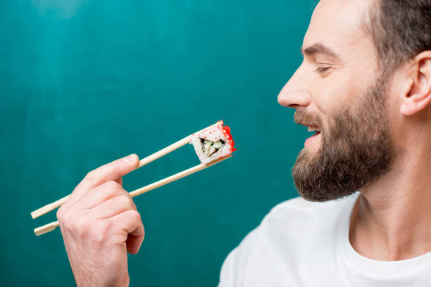 mann mit sushi - eating men food chopsticks stock-fotos und bilder