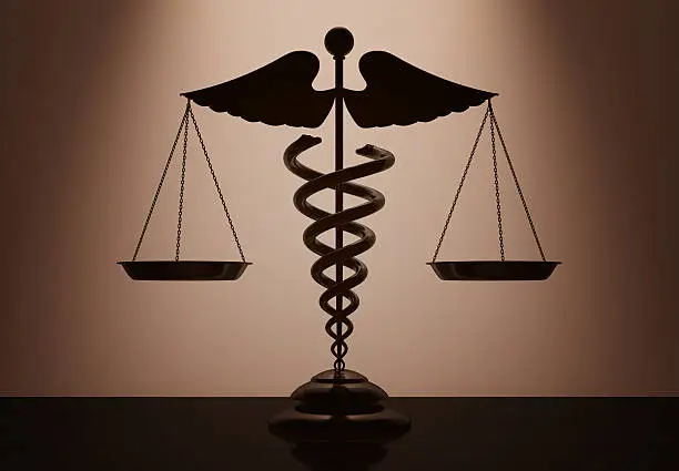 Photo of Medical Caduceus Symbol as Scales with backlight over Wall