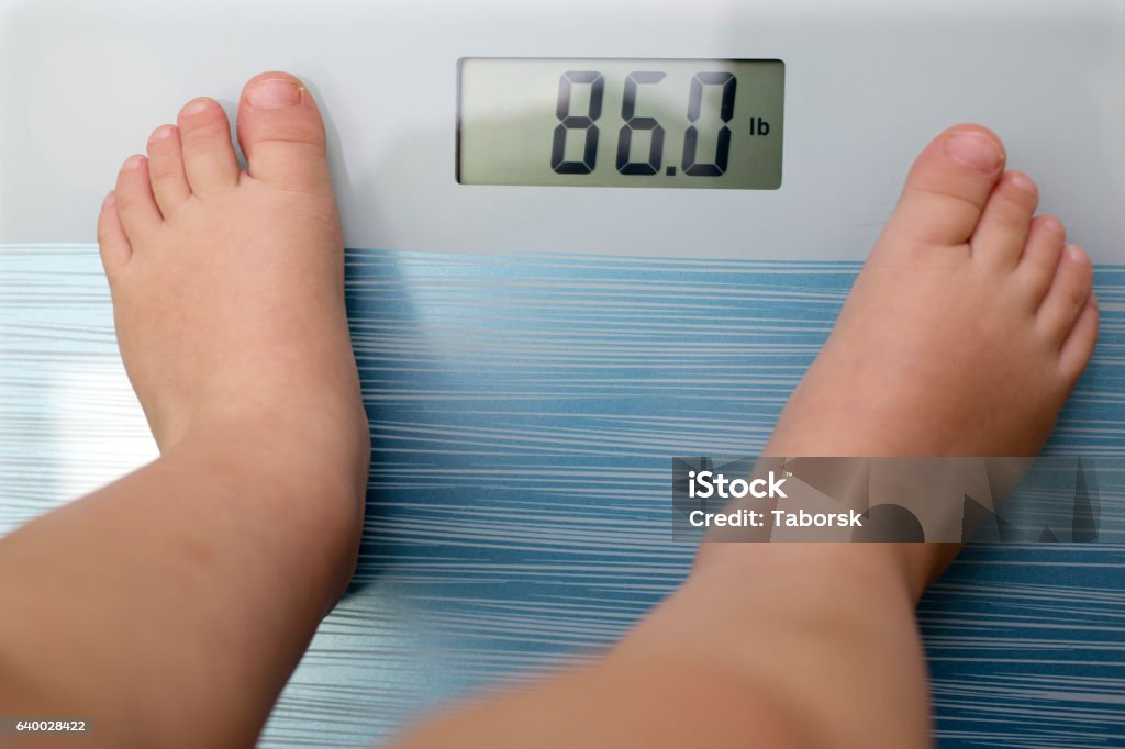 Children overweight Children overweight, young boy on a bathroom scale, Overweight Stock Photo