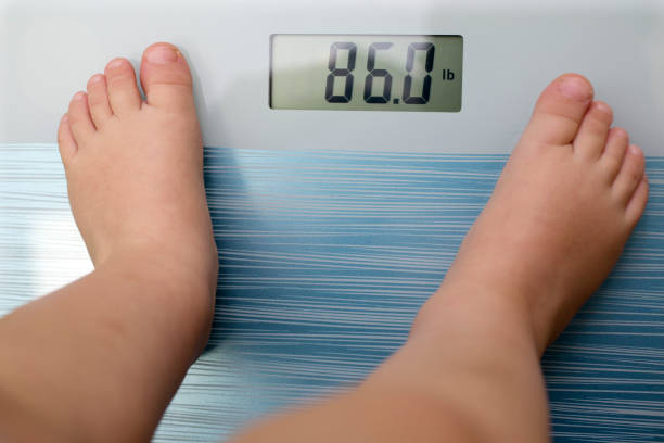 Children overweight Children overweight, young boy on a bathroom scale, overweight child stock pictures, royalty-free photos & images