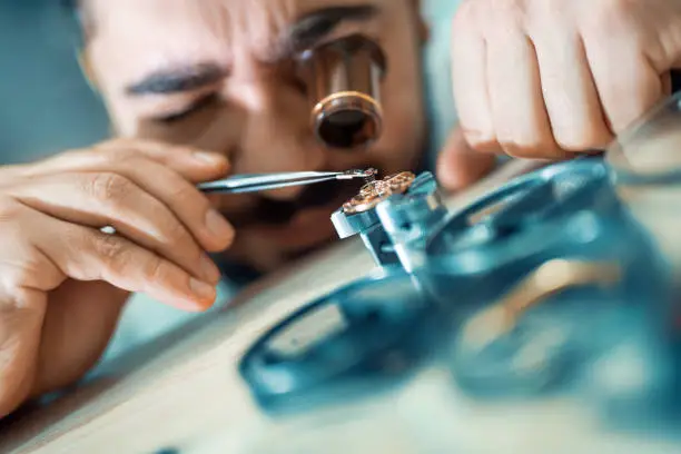 Close up portrait of a watchmaker at work.A watchmaker or repair man in action,viewing very closely a swiss watch.