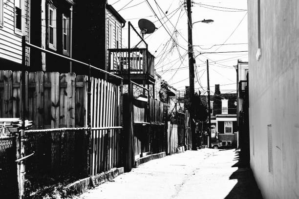 B/W photo of barb wire and razor wire lining a chain link fence.