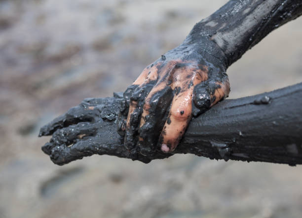Smearing black healing mud on the arm.