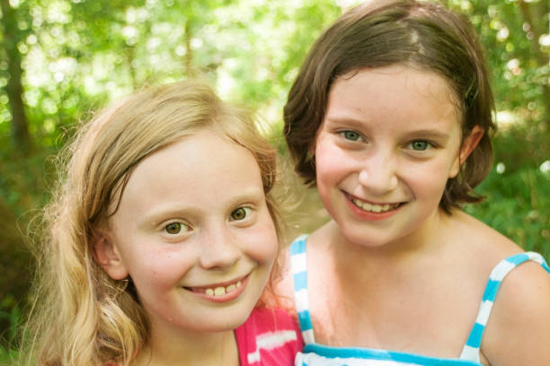 Smiling young friends Two sweating Caucasian girls aged 11 years smile at the camera while hiking on a forested trail on a hot day, Indiana, USA hazel blue eyes stock pictures, royalty-free photos & images