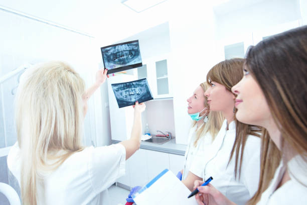 dentists and a student examining an x ray image - medical exam doctor patient adult imagens e fotografias de stock