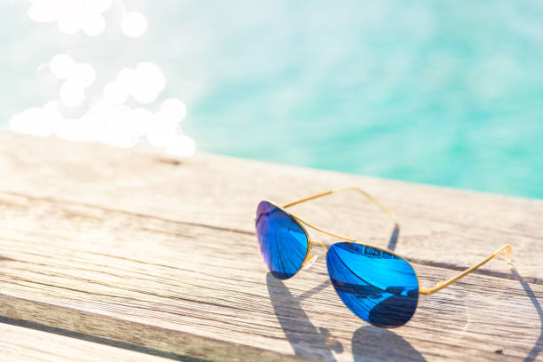 Blue Sunglasses on wooden decking by seaside stock photo
