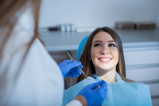 Smiling young cheerful woman waiting for a dental exam. Two people, unrecognizable dentist