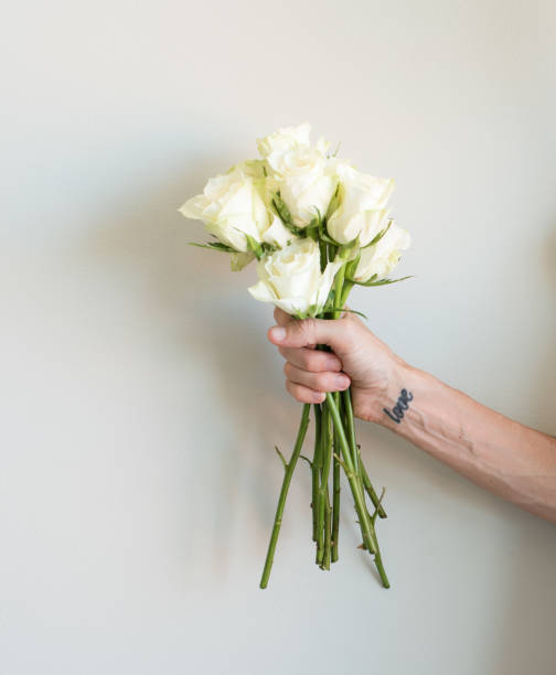 istock Hand with love tattoo holding cream roses 640060682