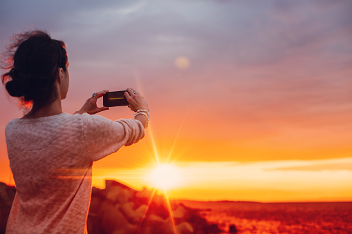 Girl taking a photo of the sunset with mobile phone