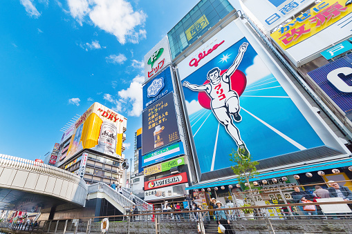 Osaka, Japan - April 14, 2016 : Tourists observe the famed advertisements of Dotonbori Canal. With a history dating from 1612, the district is now one of Osaka's primary tourist destinations.
