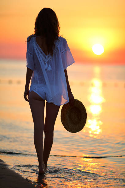 istock Slim woman walking on the beach at sunset 640069412