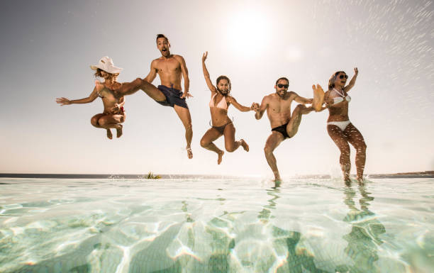 istock Below view of playful friends jumping into the pool. 640069532