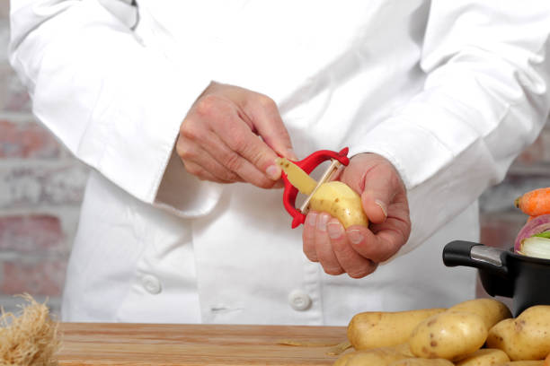 Chef peeling potatoes with a peeler in a restaurant kitchen preparing ingredients for a meal