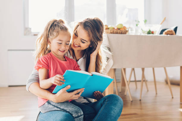 Mother and daughter reading book Mother and daughter reading book on the floor. 4 year old girl stock pictures, royalty-free photos & images