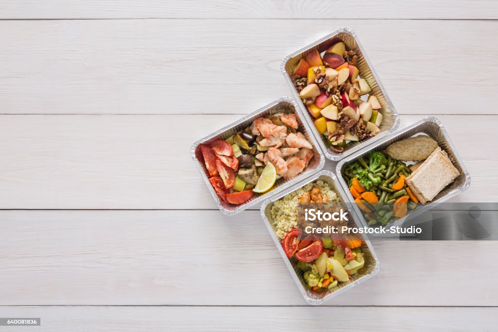 Healthy food take away in boxes, top view at wood Healthy restaurant food background. Eating right concept. Fresh diet daily meals delivery. Fitness nutrition, vegetables, fish and fruits in foil boxes. Top view, flat lay on wood with copy space Box - Container Stock Photo