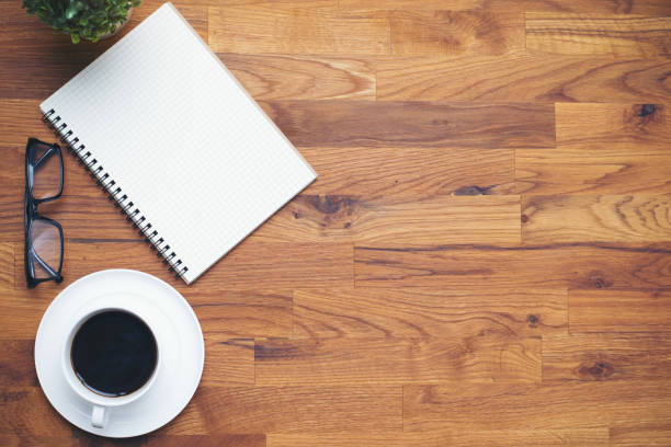istock Coffee cup and notebook lens  on wooden table background 640084440
