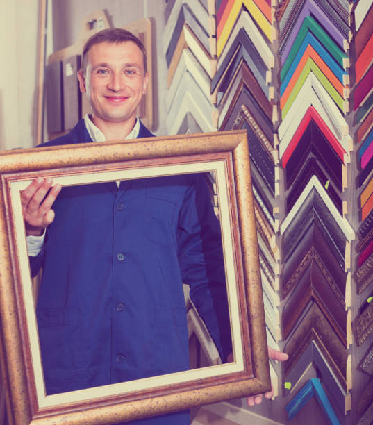 istock Man worker holding picture frame details on counter 640088908
