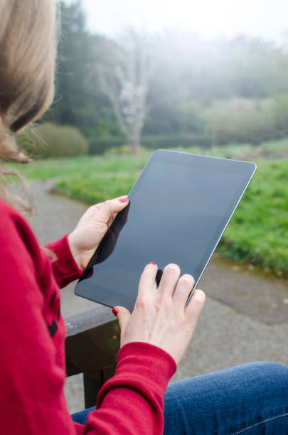 istock Blond woman is looking at a blank tablet computer outdoors 640091852