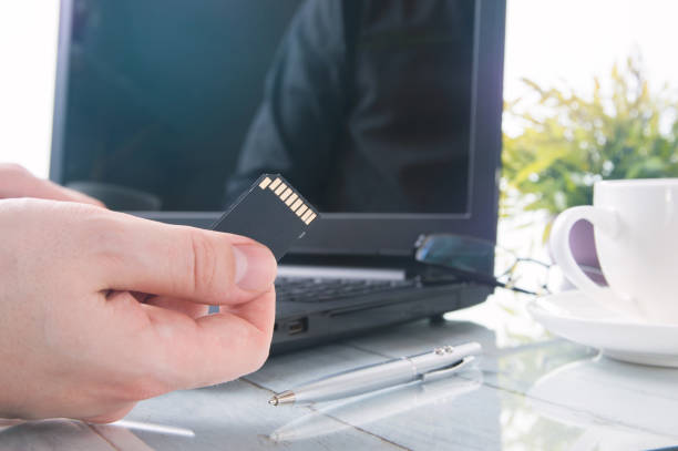 istock Man's hand is holding SD card against laptop 640092038