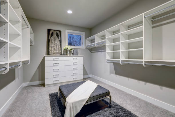istock Huge walk-in closet with shelves, drawers and gray bench. 640092262