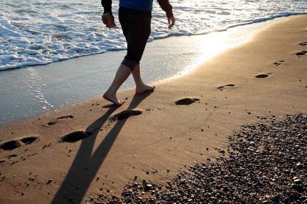 젊은 남자 걷기 해변 - men footprint beach sunset 뉴스 사진 이미지