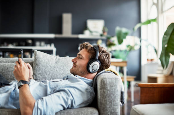 Streaming some new music Cropped shot of a handsome young man listening to music on his mobile phone at home headphones stock pictures, royalty-free photos & images