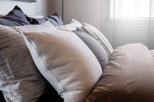 Bed maid-up with clean white pillows and bed sheets in beauty room. Close-up. Lens flair in sunlight.