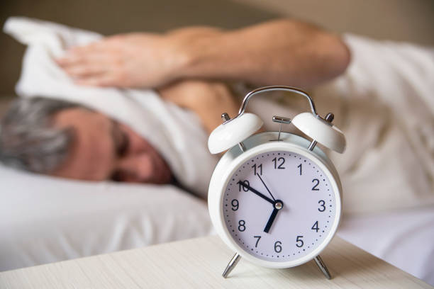 istock sleeping man disturbed by alarm clock early morning. 640097438