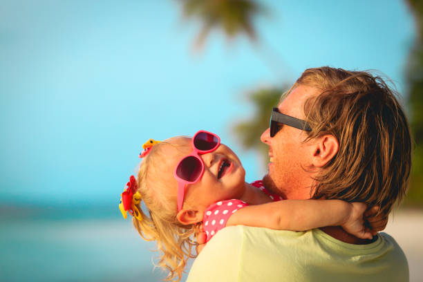 istock father and cute little daughter loving hug at beach 640104096