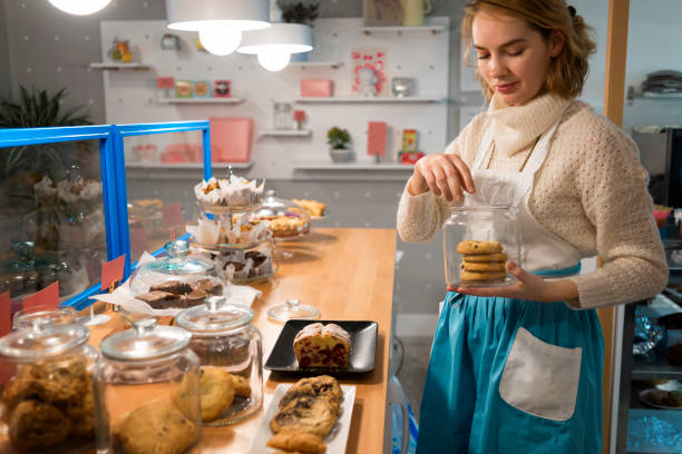 image of a pretty waitress choosing a perfect cookie stock photo