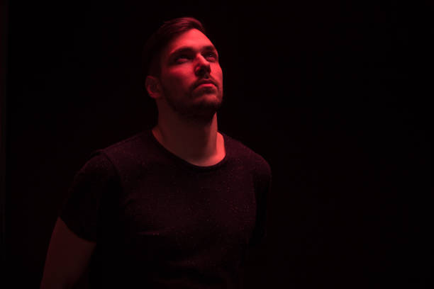 istock one man looking above up, red color light 640109182