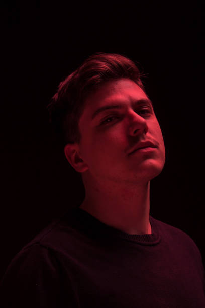 istock one man looking above up, red color light 640109748