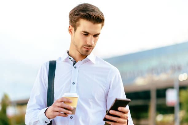 istock Serious handsome businessman using phone on street 640109992