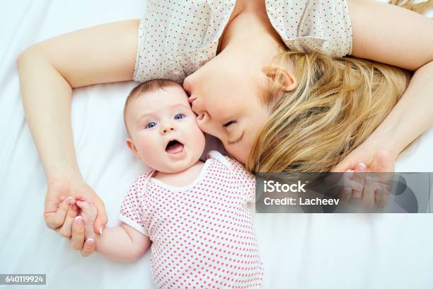 Mother Kisses Baby Lying On The Bed Closeup Stock Photo - Download Image Now - Mother, Baby - Human Age, Newborn