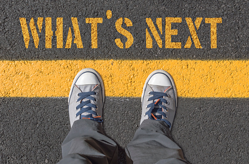 WHAT`S NEXT print with sneakers on asphalt road, top view.