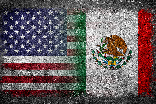 Merged Flag of USA and Mexico painted on grunge concrete. Concept of President's US immigration policy to erect concrete wall along Mexico border.