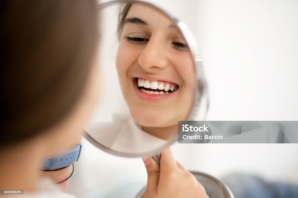 Teenage girl looking at her teeth in the mirror Cute teenage girl looking at her teeth in the mirror Smiling Stock Photo