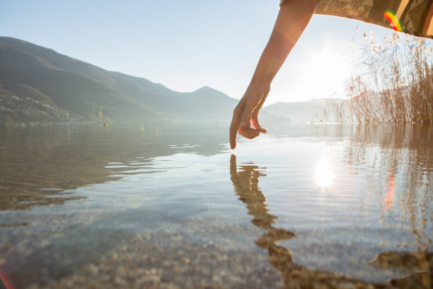 istock Finger touches surface of mountain lake 640133822