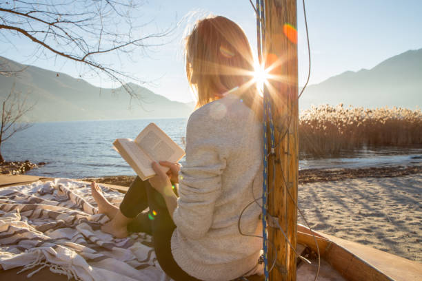 istock Young woman relaxing by the lake reading book 640134542